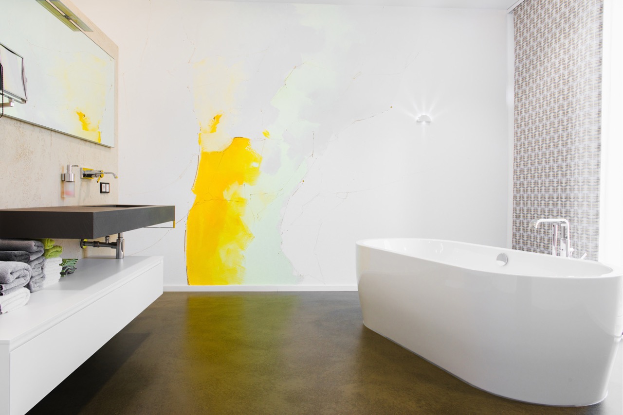 Modernes fugenloses Bad mit gelbem Farbakzent an Wand
