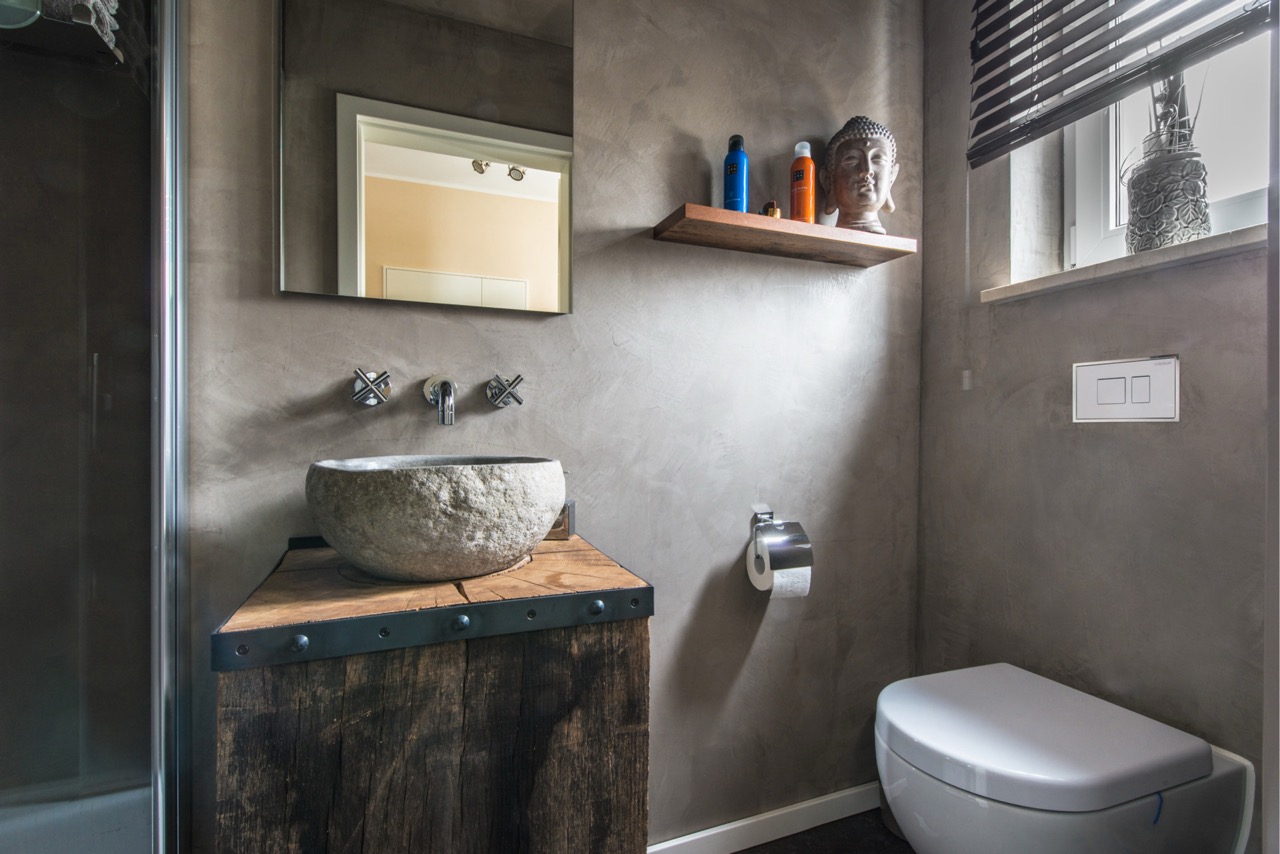 WC mit dunkler fugenloser Wandgestaltung und Steinwaschbecken