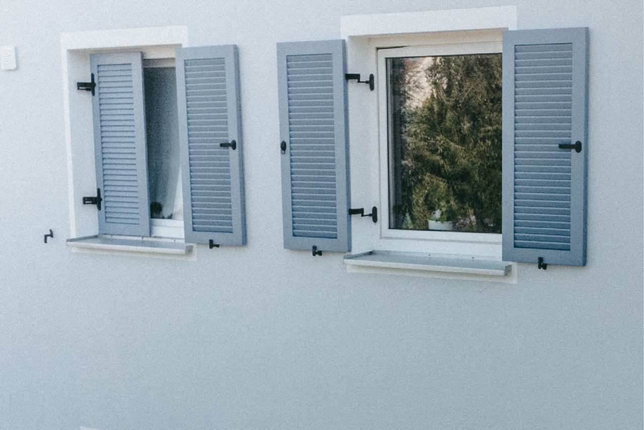 Hellgrau-Weiße Fassade mit blauen Fensterläden