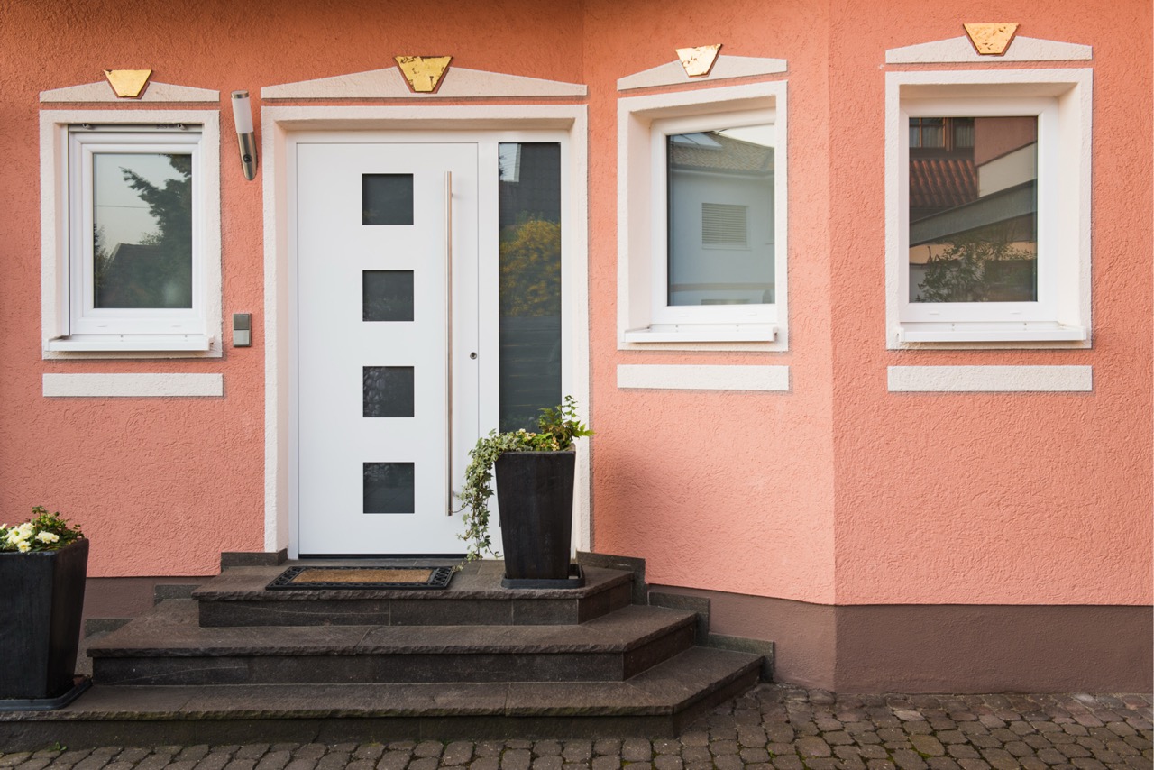 Wohnhauseingang mit rosafarbener Fassadengestaltung