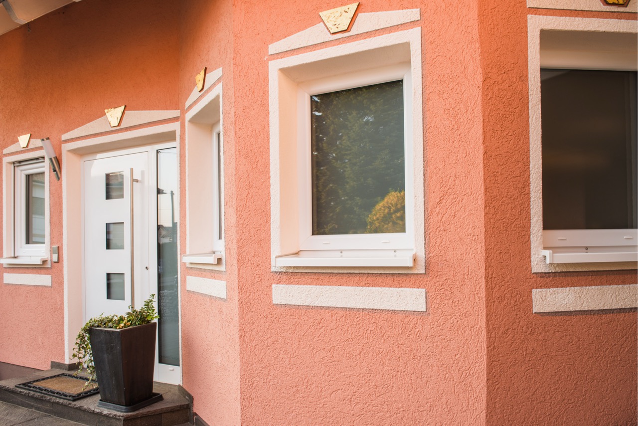 Fenster und Eingang an rosafarbener Wohnhausfassade