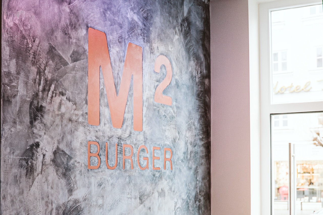 Burger-Restaurant mit Betonoptik und Logo an der Wand